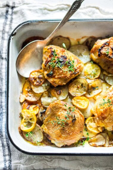 These easy oven-baked chicken thighs are roasted over thinly sliced potatoes with garlic, lemon and thyme. A delicious, easy sheet pan dinner with only 10 minutes of prep time, before baking in the oven. 