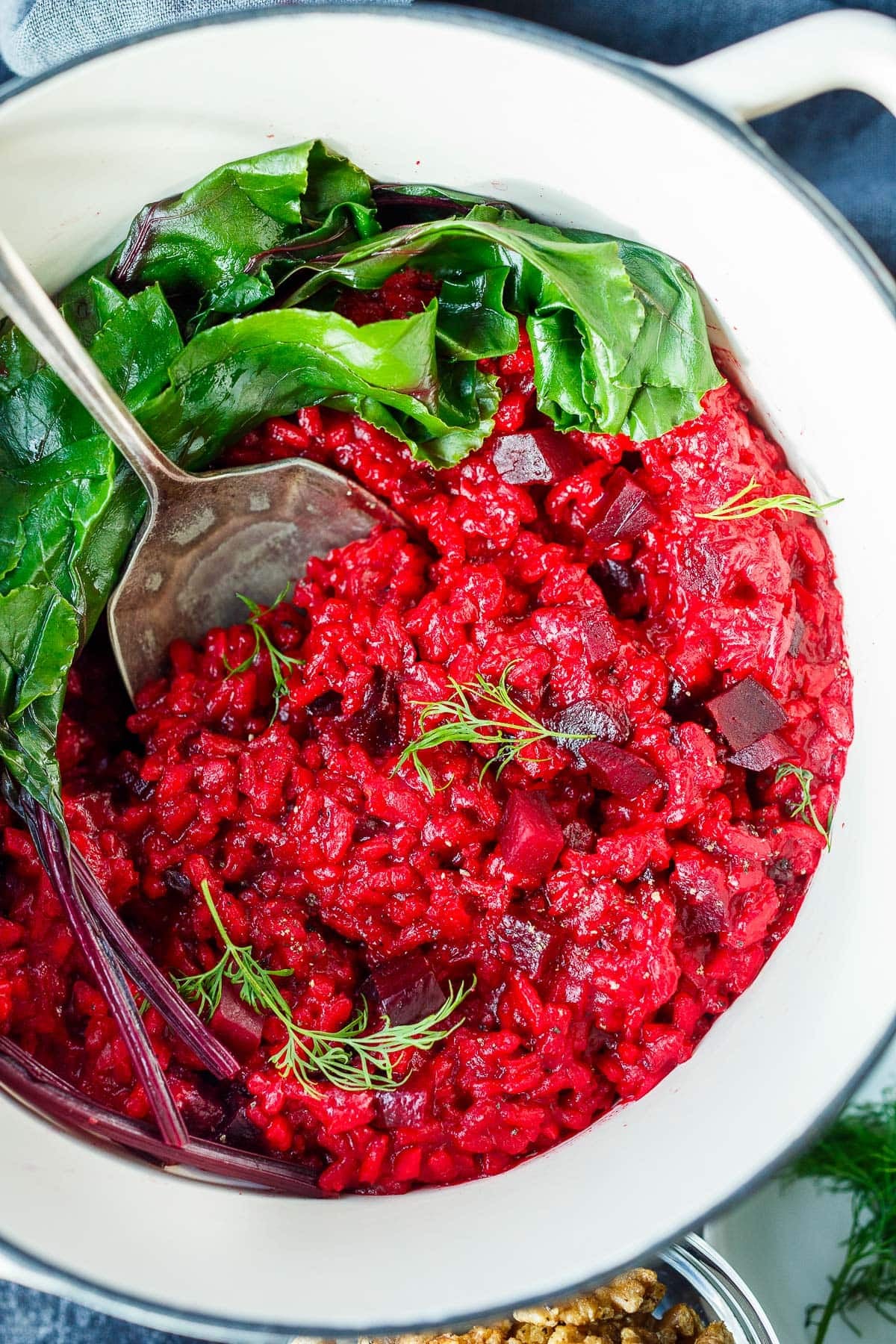 dutch oven with beet risotto with steamed beet greens, garnished with fresh dill. 