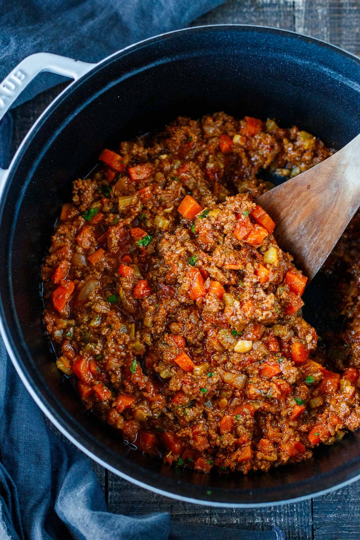wood spatula in pot with simmer bolognese sauce.