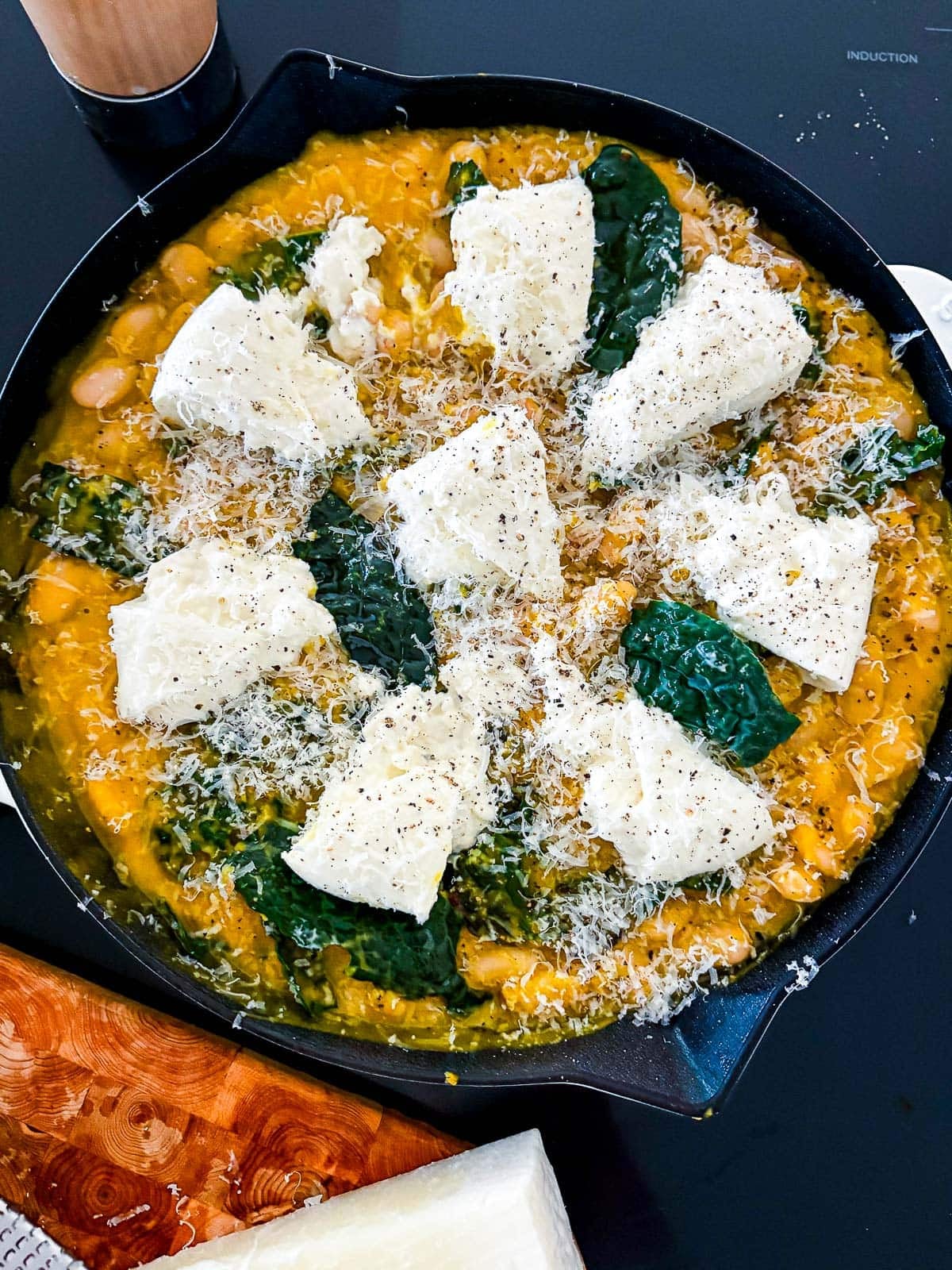 skillet with butternut squash sauce and white beans topped with kale, burrata, and pecorino.
