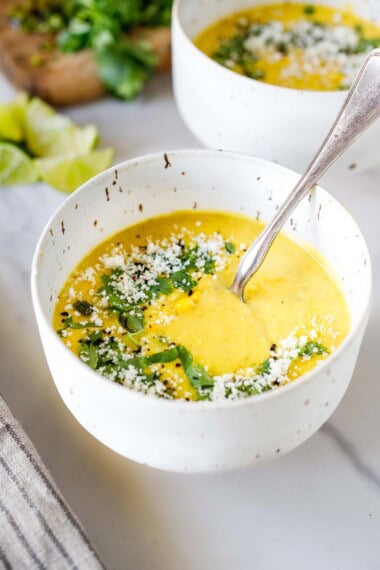 This easy corn soup recipe is the best summer tradition! Use fresh corn or frozen corn; it's creamy, delicious, and vegetarian. Topped with cilantro, cotija and lime.