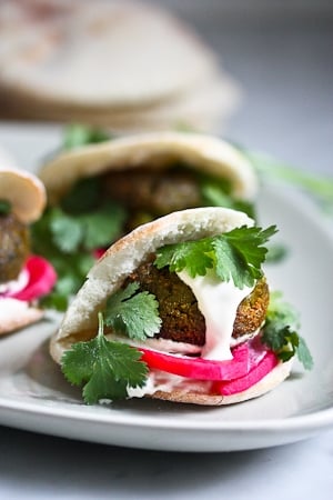 falafel in a small pita wrap with parsley, pickled onions, and tahini sauce.