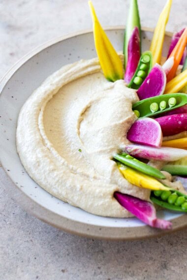 Hummus with veggies in a white bowl