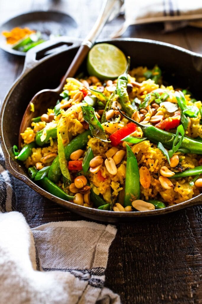 bowl of Indian fried rice with peanuts, snap peas, chilies, and scallions.