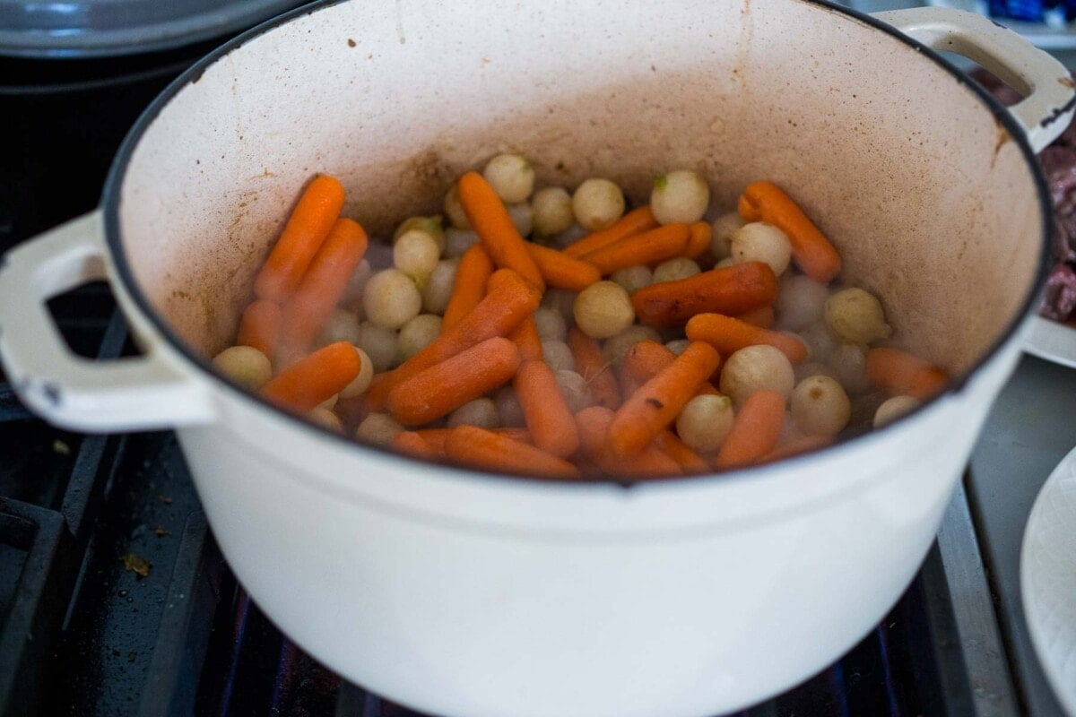 onions and carrots cooking in a dutch oven.