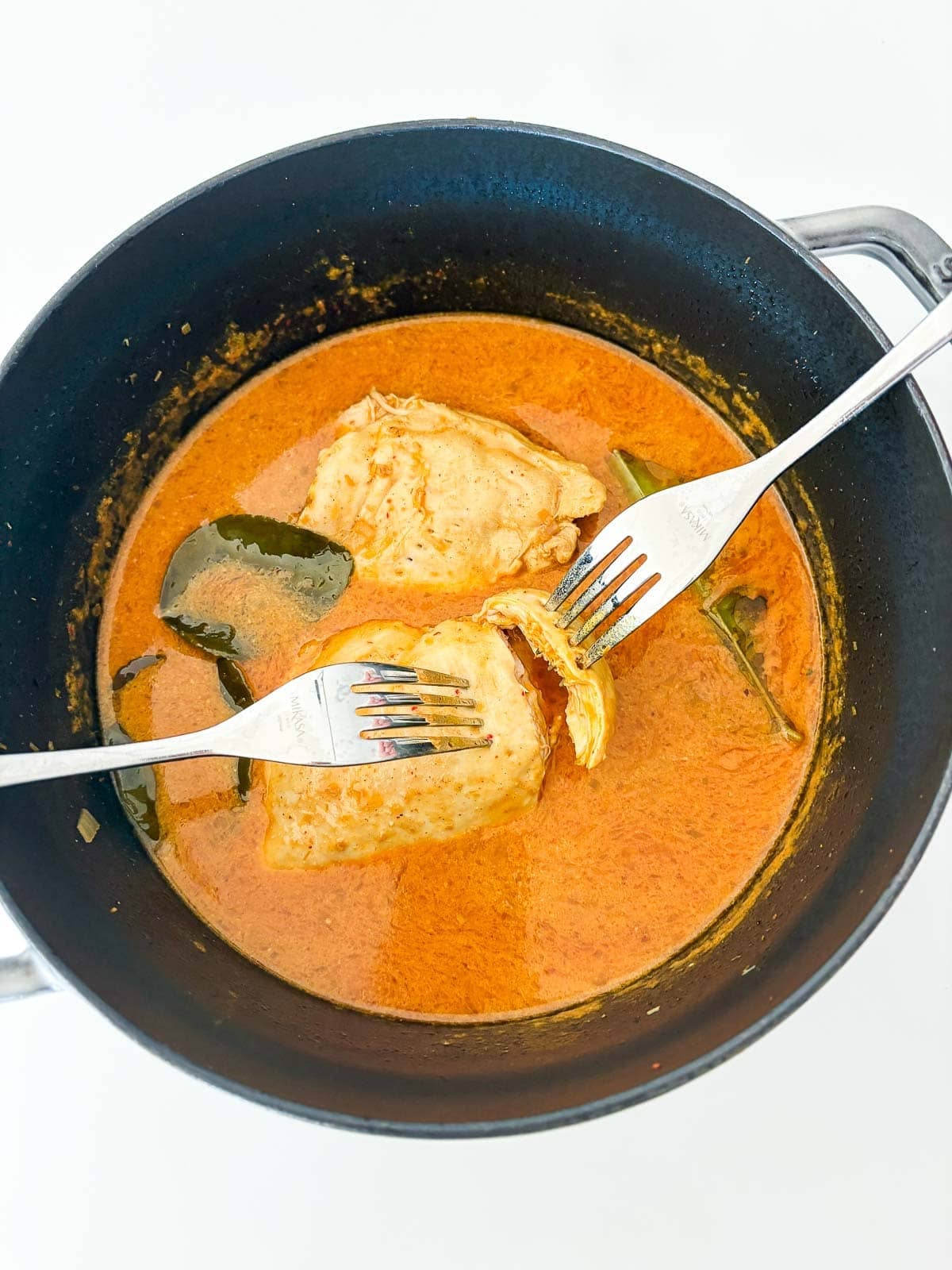 Shredding the chicken breast with two forks.