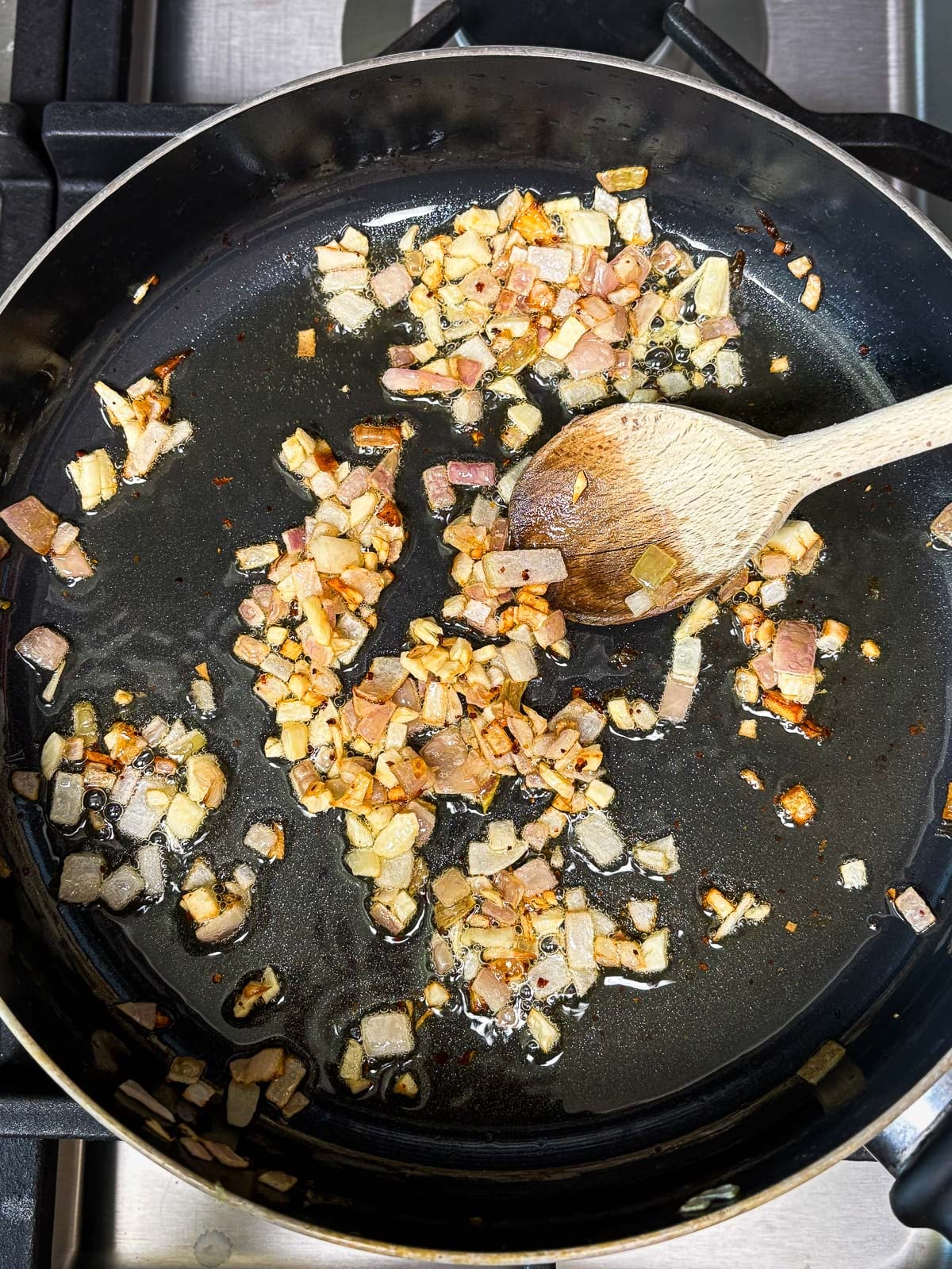 sautéing aromatics, garlic and shallot, in skillet with oil using a wood spoon.