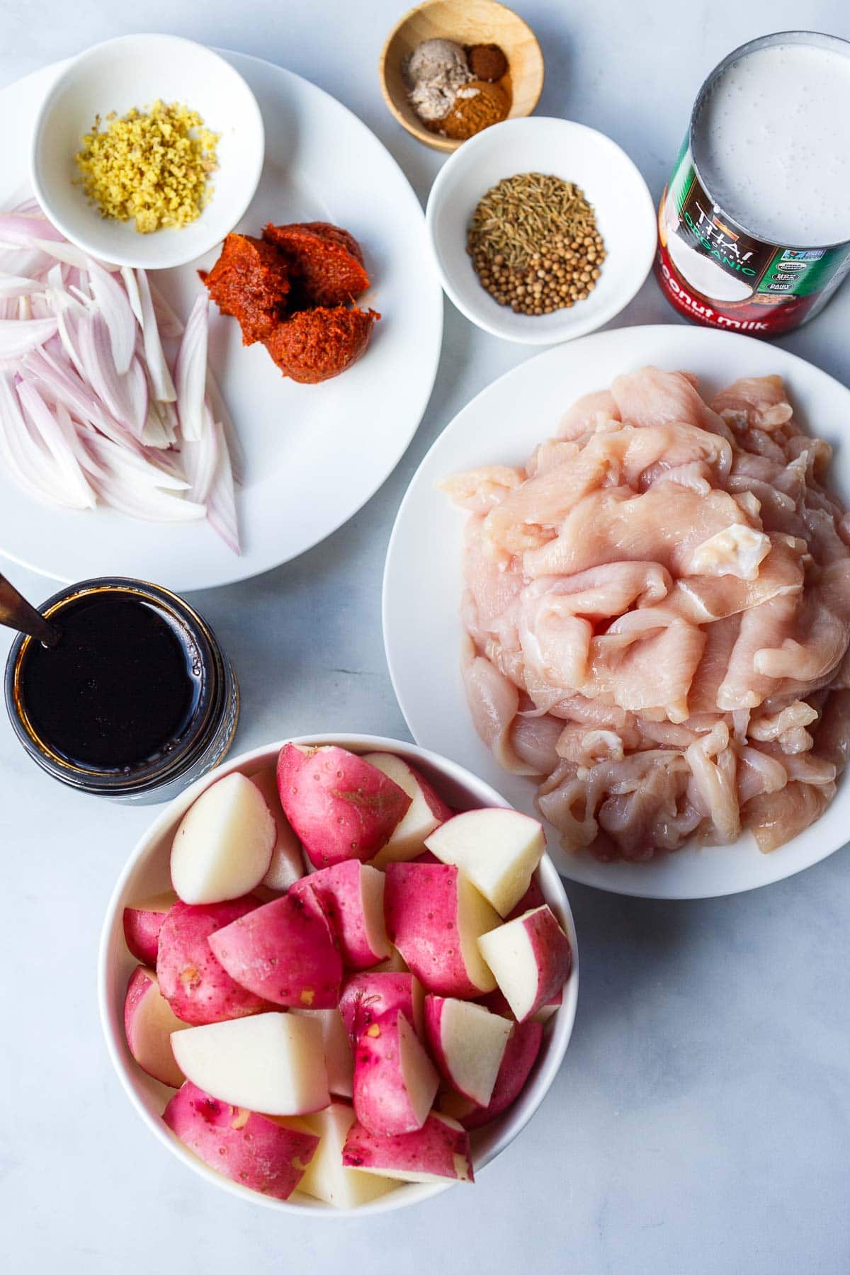 ingredients prepped and measured to make thai massaman curry - spices, seeds, ginger, curry paste, shallots, chicken, potatoes.