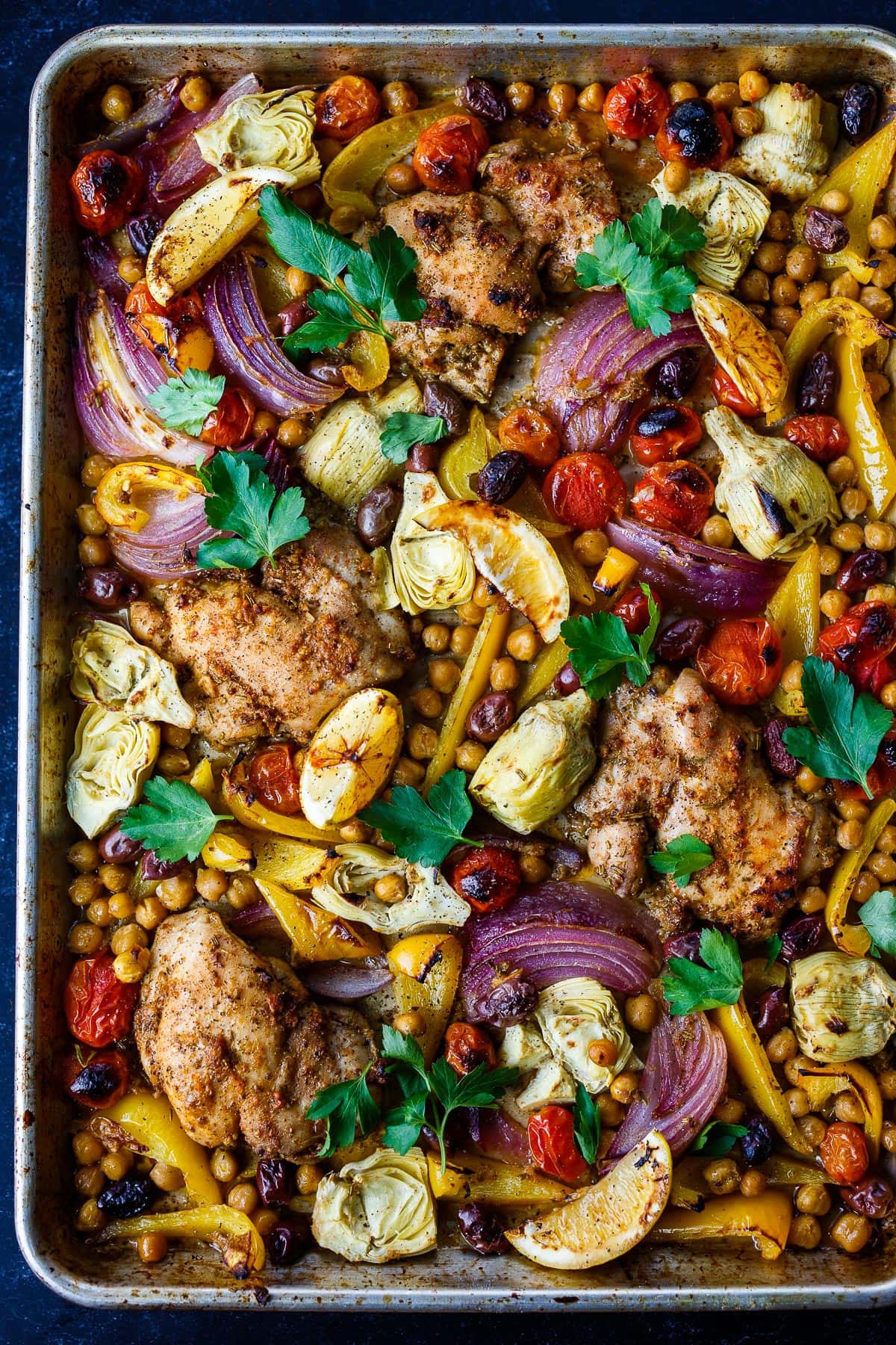 Mediterranean Chicken with veggies, chickpeas, olives and herbs. A delicious Sheet Pan Dinner.