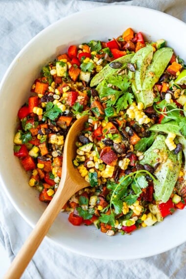 This roasted sweet potato salad recipe is punchy and flavorful! With fresh corn, zucchini, peppers, avocado & cilantro w/ cumin lime dressing.