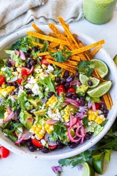 This vegetarian taco salad recipe is healthy and easy-made w/ black beans, tomatoes, corn, avocado, crisp romaine & zesty cilantro lime dressing.