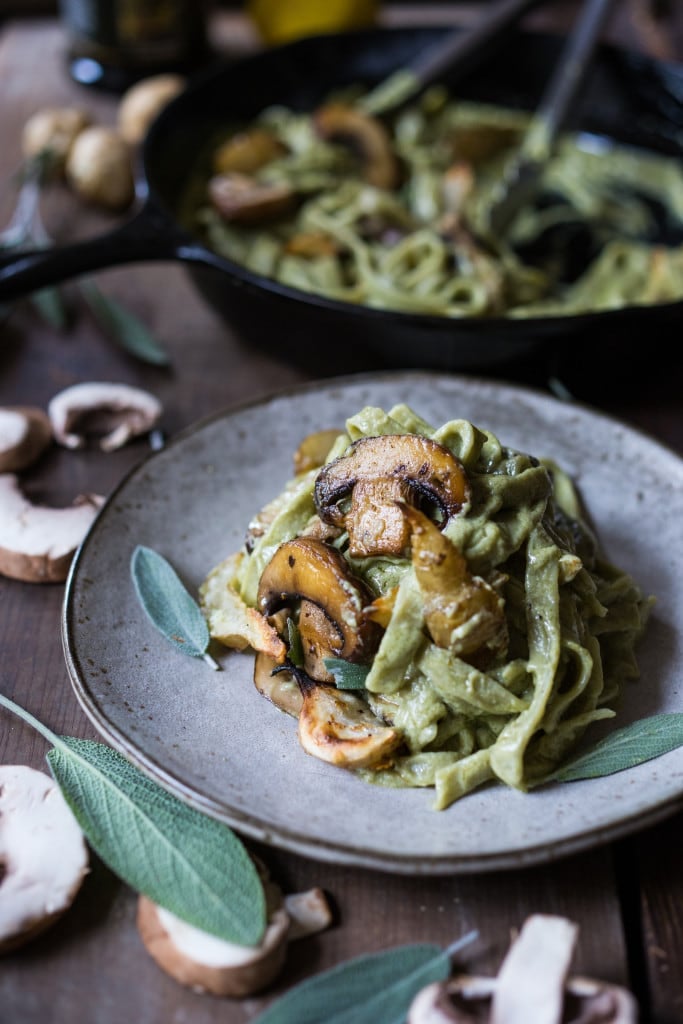 plate of creamy vegan mushroom artichoke pasta with seared mushrooms and sage leaves.