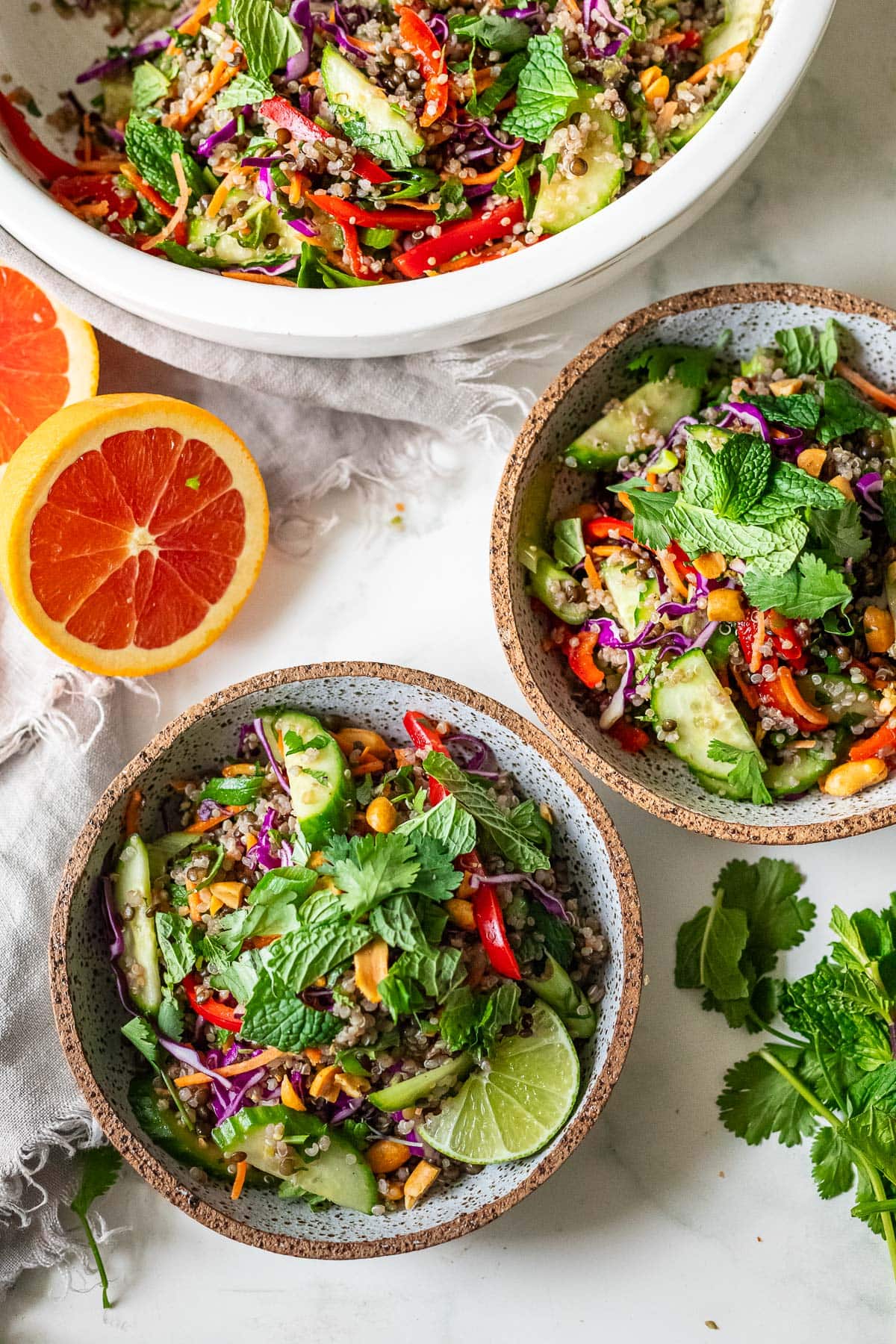 two small bowls with thai quinoa lentil salad garnished with cilantro and mint and lime wedges.