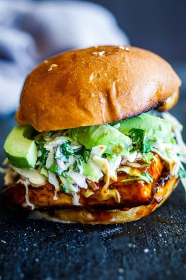 A crispy tofu burger with bbq sauce,, slaw and avocado on a plate.
