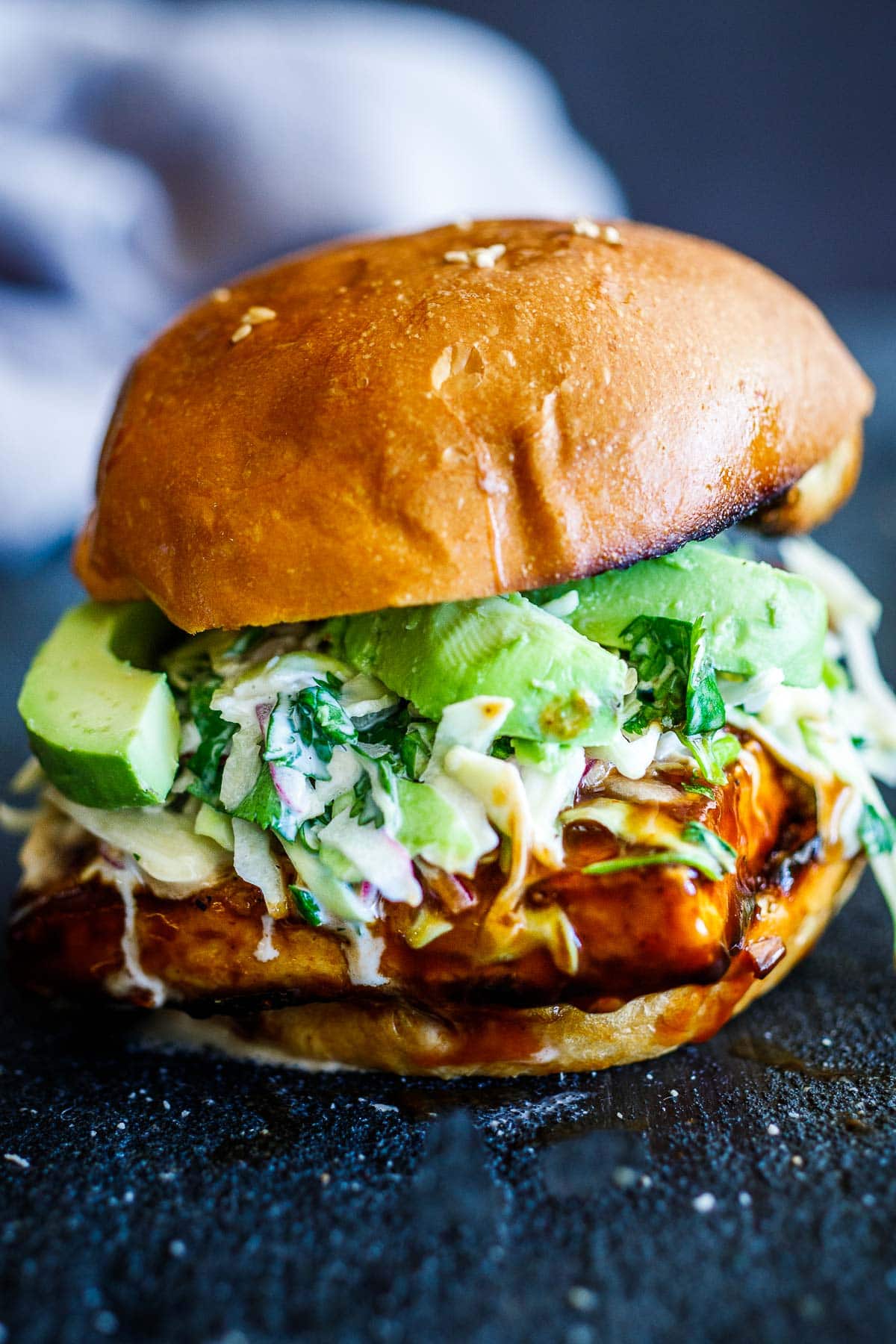 bbq tofu sandwich on brioche with slaw and sliced avocado.