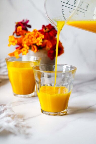 Delicious and immune-boosting, this ginger turmeric shot recipe is easy to make at home! Made with fresh turmeric root, ginger, orange, lemon, and black pepper- use it to soothe a cold, fight inflammation, and revitalize and energize. Sunshine for the soul! 