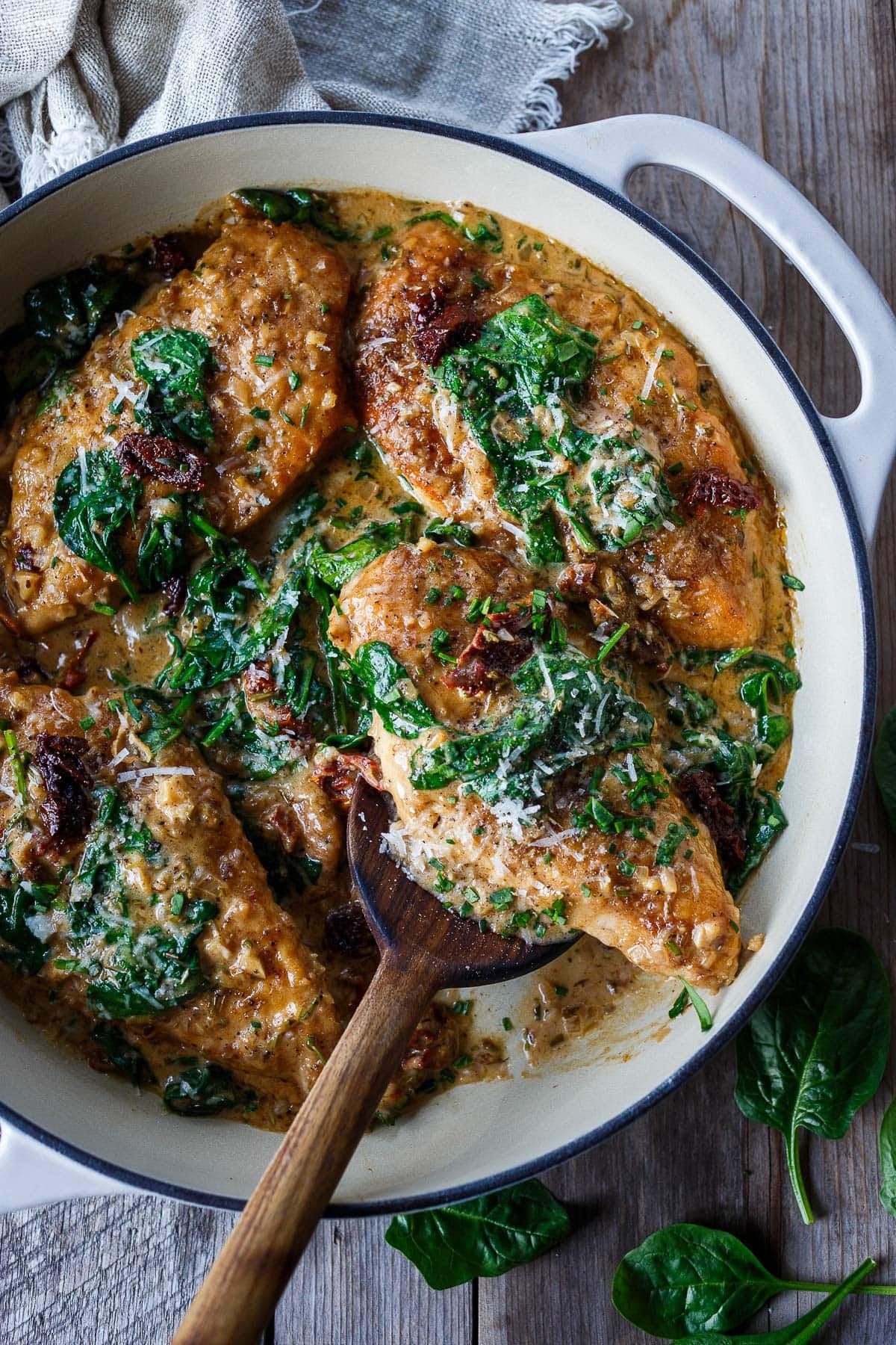dutch oven with creamy Tuscan chicken with sauce, spinach, sun-dried tomatoes, and pecorino. 