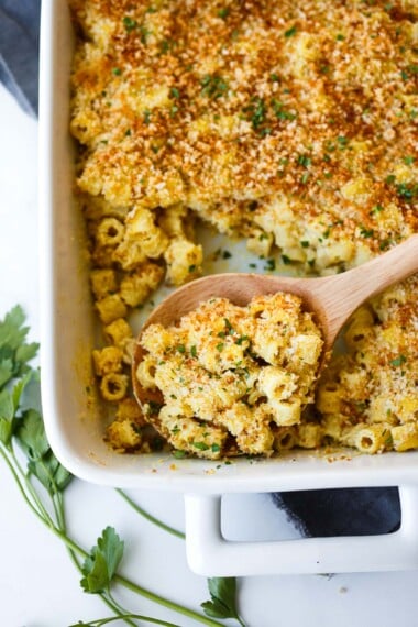Vegan mac and cheese in a baking dish with a wood spoon.