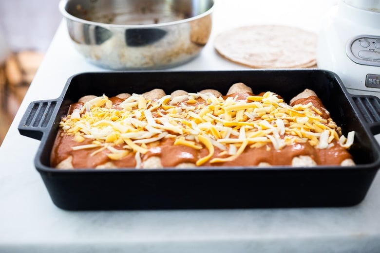 Adding the cheese to the top of the enchiladas. 